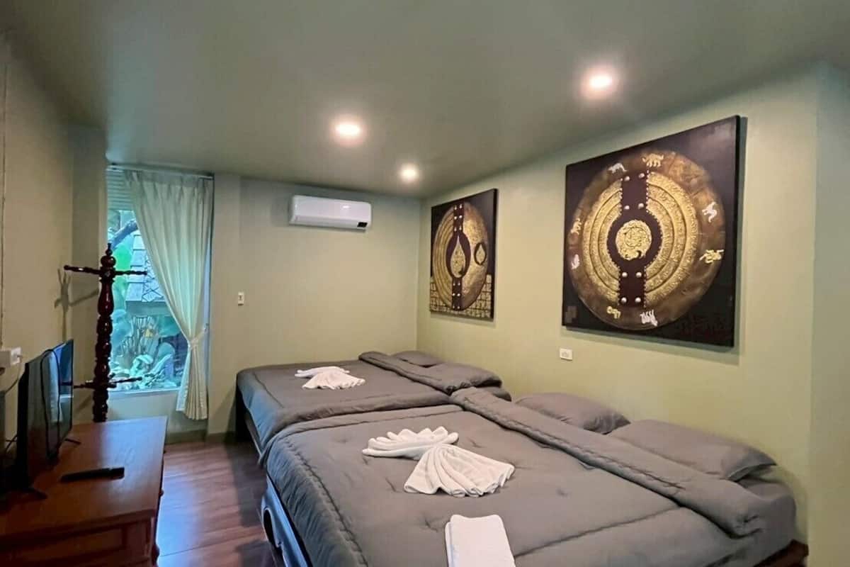 Habitación de hotel con dos camas, un escritorio y obras de arte en las paredes.