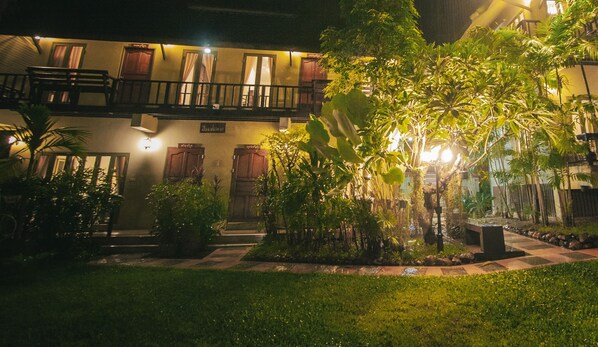A hotel courtyard at night with a well-lit garden area, a pool, and a two-story building with balconies. - Pai Panalee The Nature Boutique Hotel (Pai)