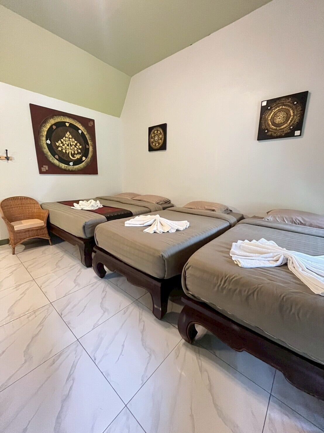 A room with three beds, a chair, and decorative wall art.