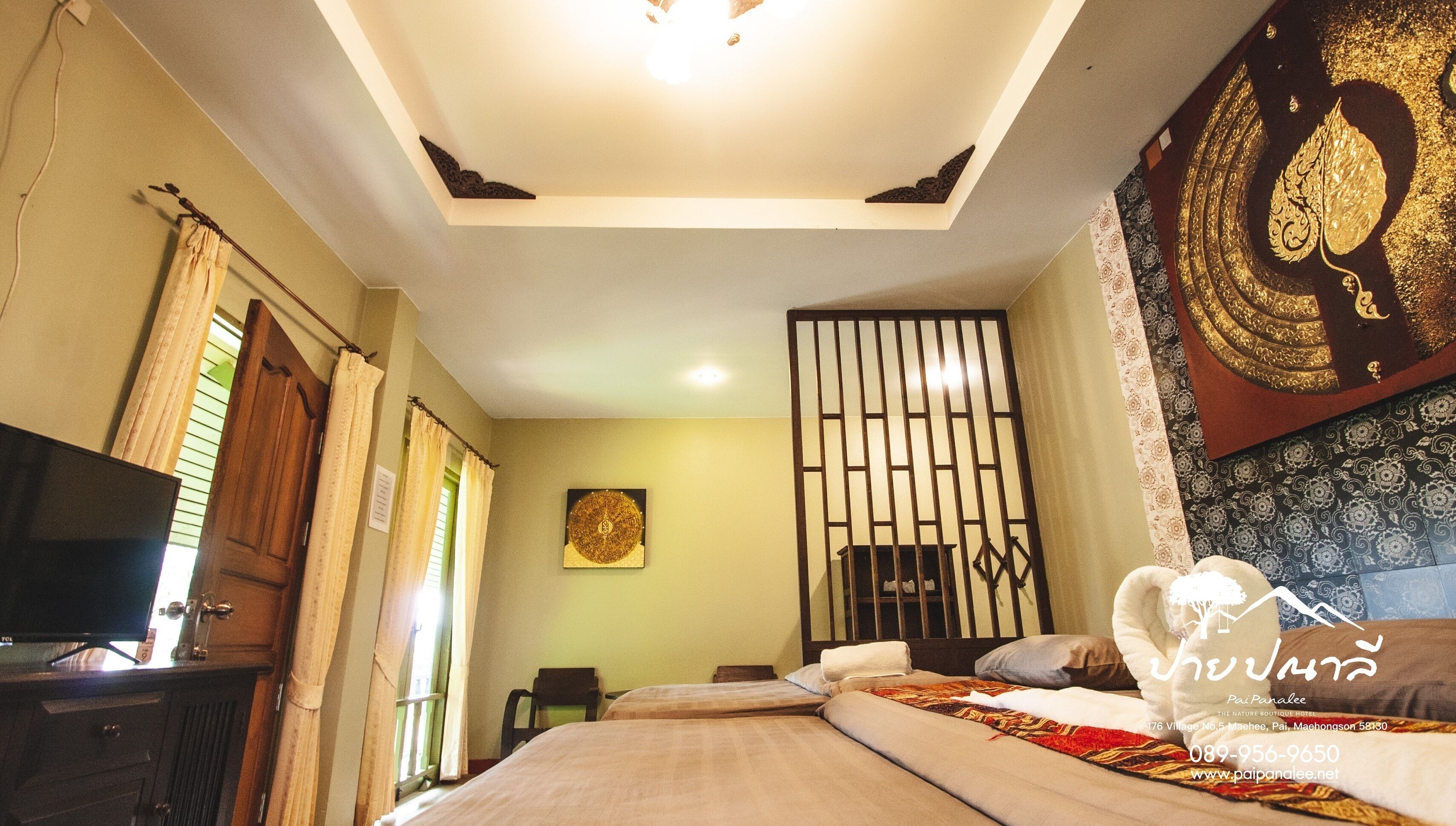 A hotel room with a bed, a television, curtains, a decorative wall, and a window with blinds.