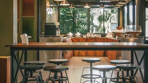 Un restaurante con barra de madera, taburetes e iluminación colgante.