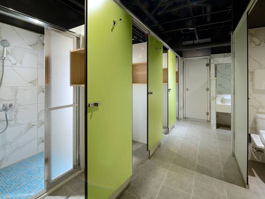 Des toilettes publiques avec des cabines individuelles, un espace douche et un lavabo.