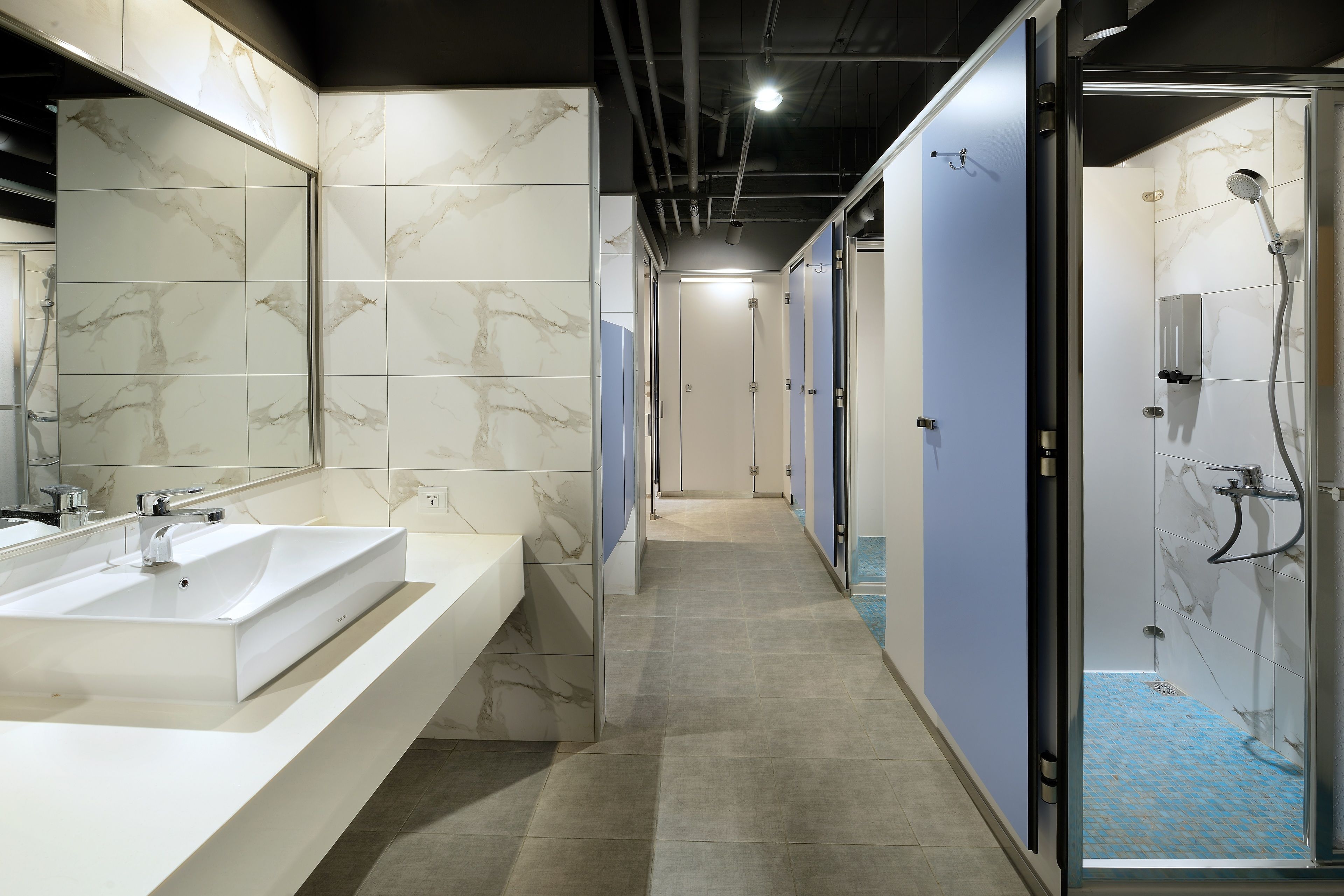 A modern bathroom with a large sink, a shower, and a mirror.