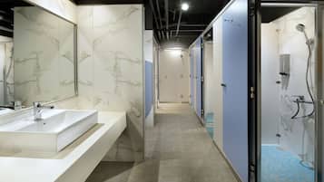 A modern bathroom with a large sink, a shower, and a mirror.