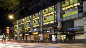 A multi-story hotel with illuminated signage, a prominent entrance, and a busy street with light trails. - Park City Inn & Hostel - Yonghe Taipei (New Taipei City)