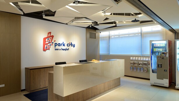 A reception desk with a logo, a vending machine, and a window with blinds. - Park City Inn & Hostel - Yonghe Taipei (New Taipei City)