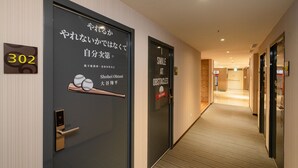 A hotel corridor with doors labeled "302" and "301". One door has a motivational poster with a baseball bat and balls, and the other has a poster encouraging to smile at obstacles. - Park City Inn & Hostel - Yonghe Taipei (New Taipei City)