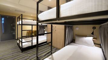 A bunk bed room with a wooden wardrobe, a desk, and a lamp.