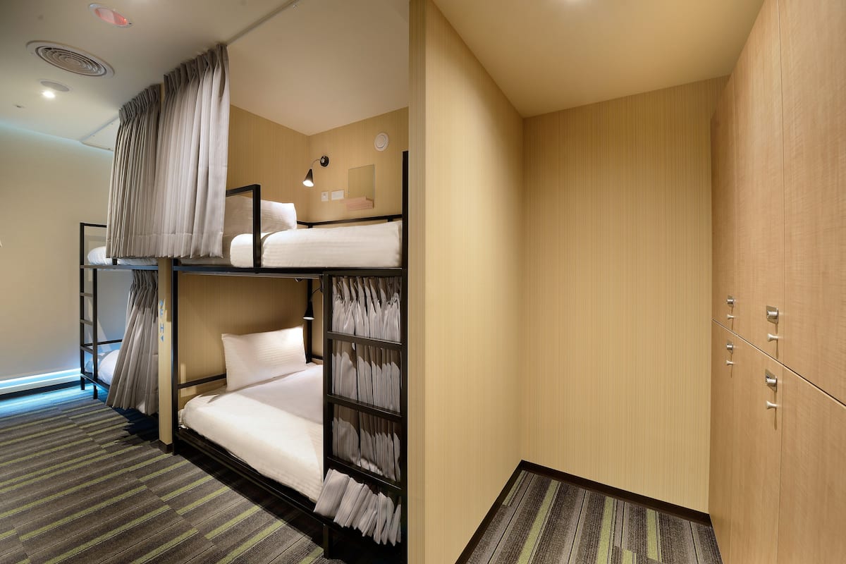 Ein Hotelzimmer mit Etagenbetten, einem Kleiderschrank und einem kleinen Schreibtisch.
