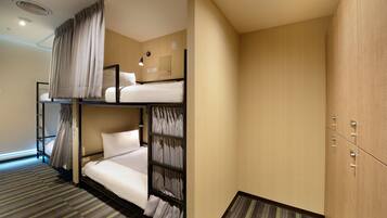 A hotel room with bunk beds, a wardrobe, and a small desk.