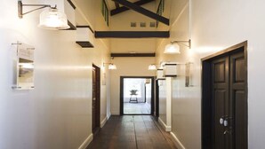 A hallway with wooden flooring, white walls, and black-framed doors. - Baan Luang Rajamaitri Historic Inn (Chanthaburi)