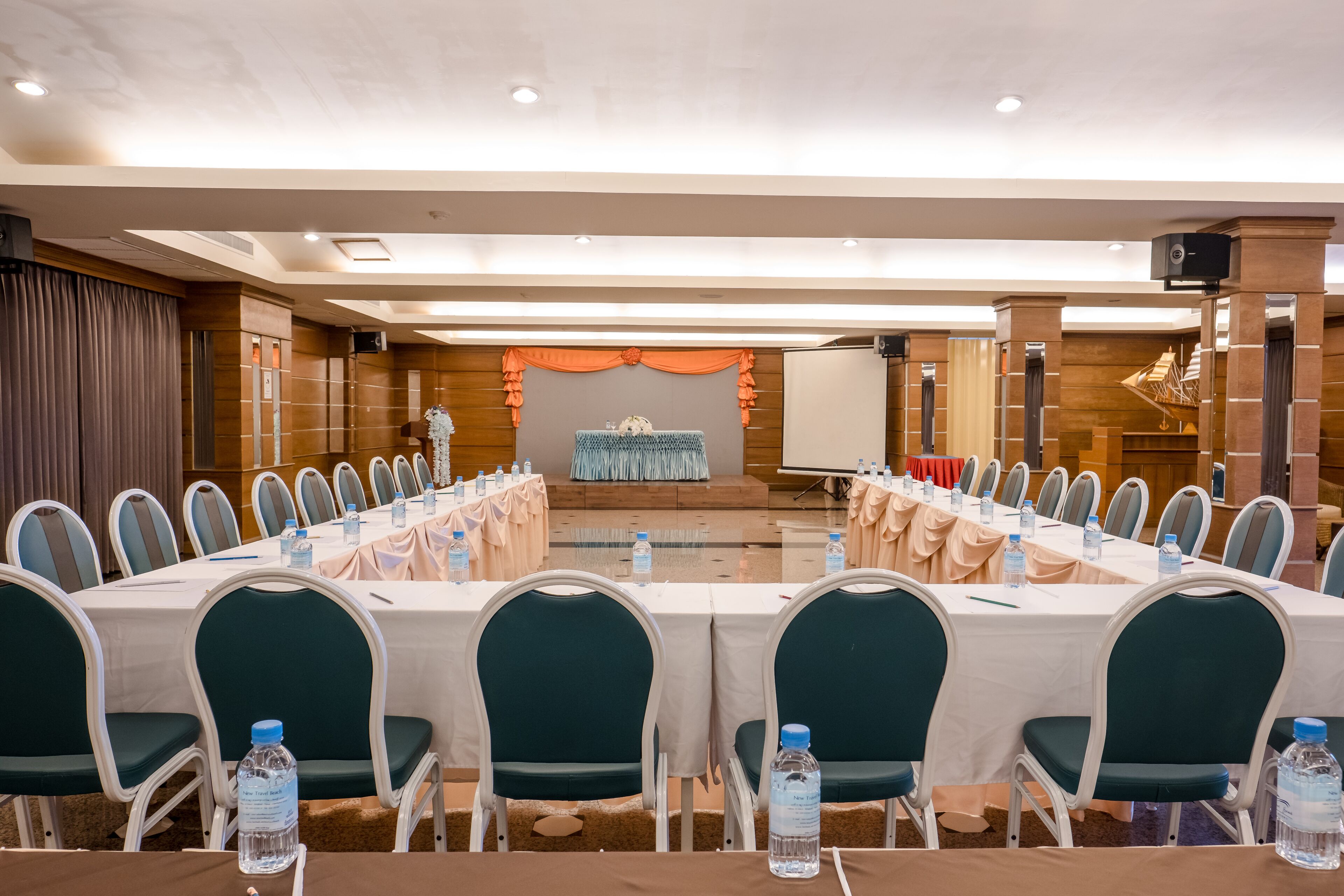 Un salón de conferencias con una larga mesa, sillas y botellas de agua.