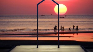 A sunset over the ocean with a silhouette of a structure in the foreground. - New Travel Beach Resort (Tha Mai)