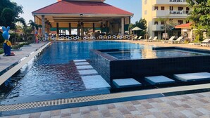 A swimming pool with a tiled deck, lounge chairs, and a covered area with a red roof. - New Travel Beach Resort (Tha Mai)