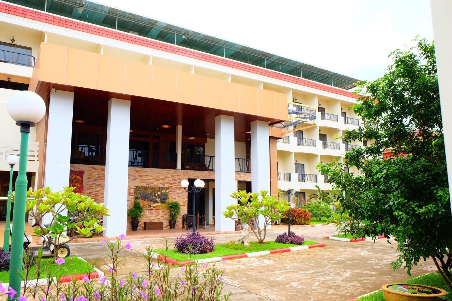 A hotel with a central courtyard, multiple balconies, and a variety of plants.