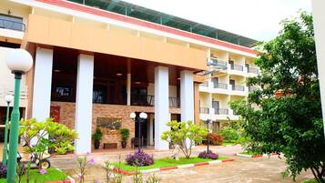 A hotel with a central courtyard, multiple balconies, and a variety of plants.