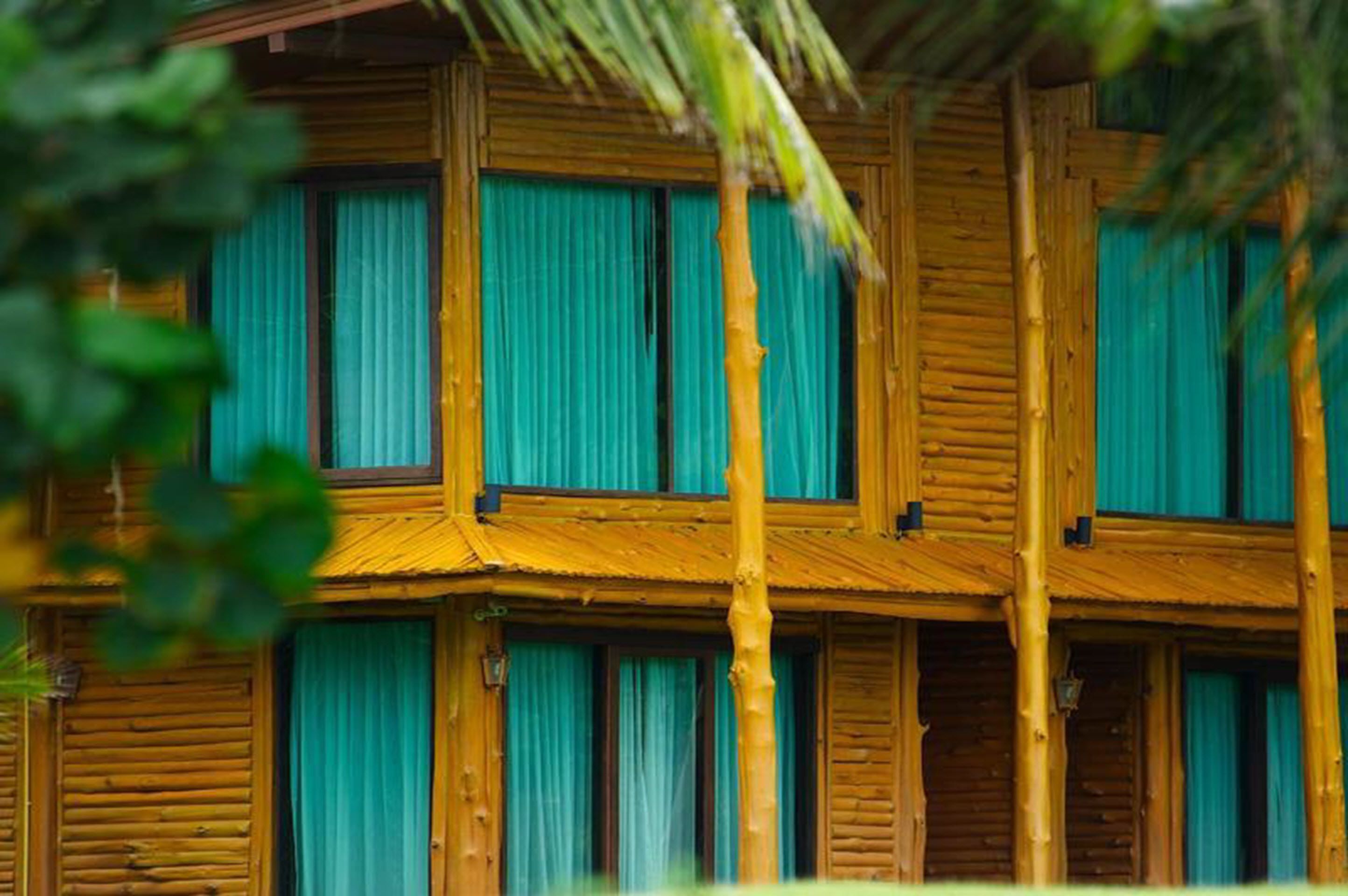 Un edificio in legno su più piani con ampie finestre e tende verdi.