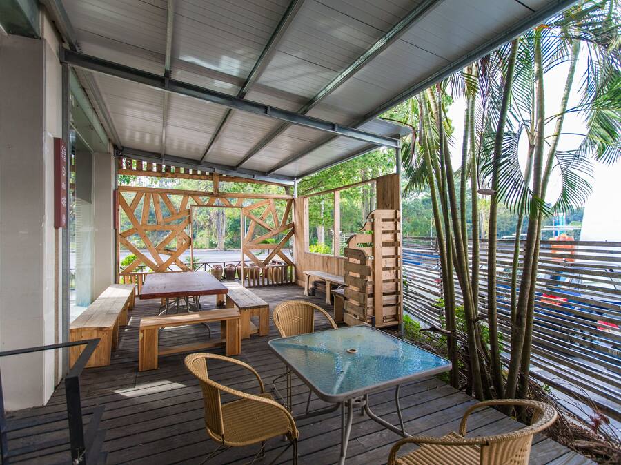 An outdoor patio with wooden furniture, a glass table, and a view of the street.