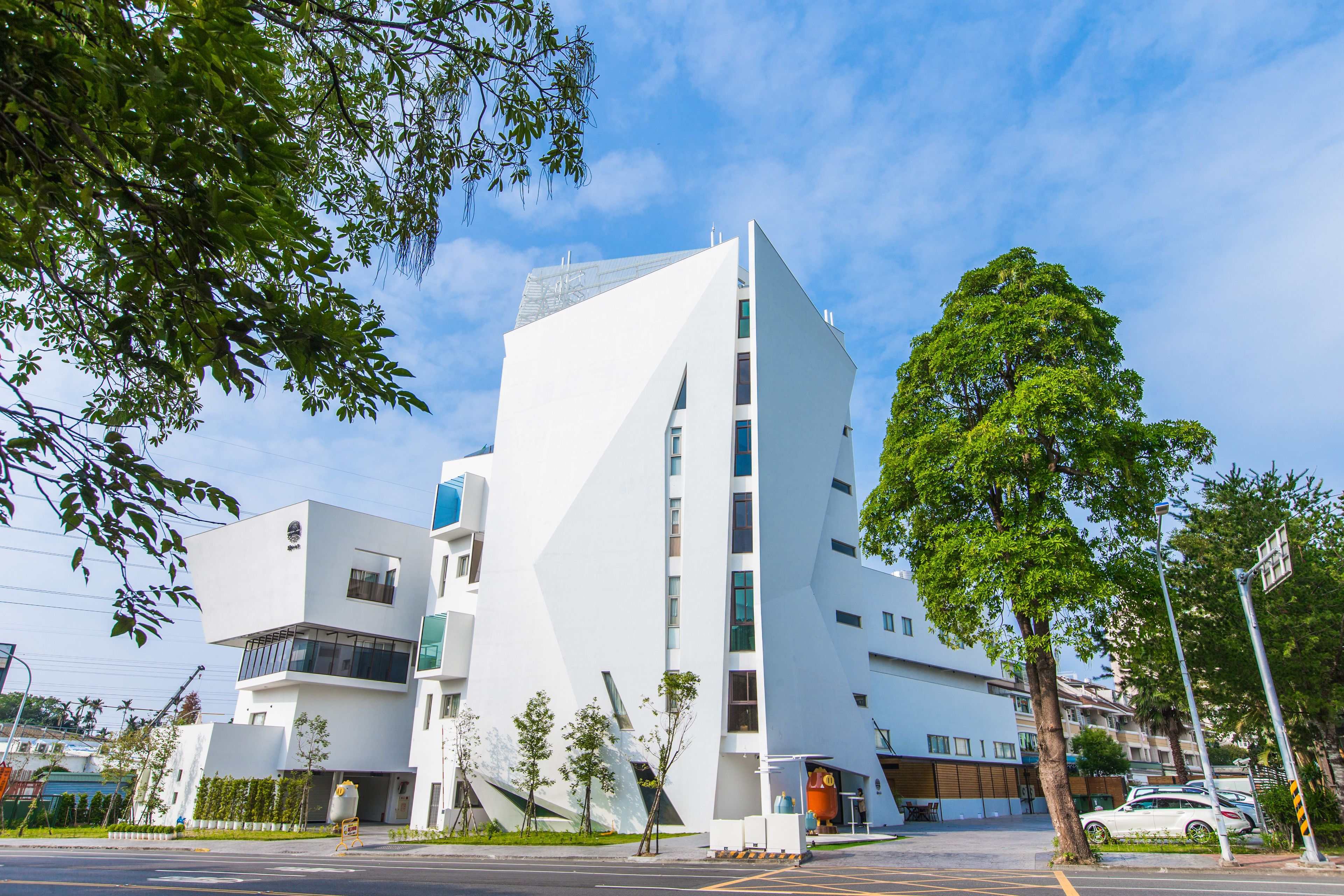 A modern building with a unique angular design, featuring multiple floors and a prominent entrance.
