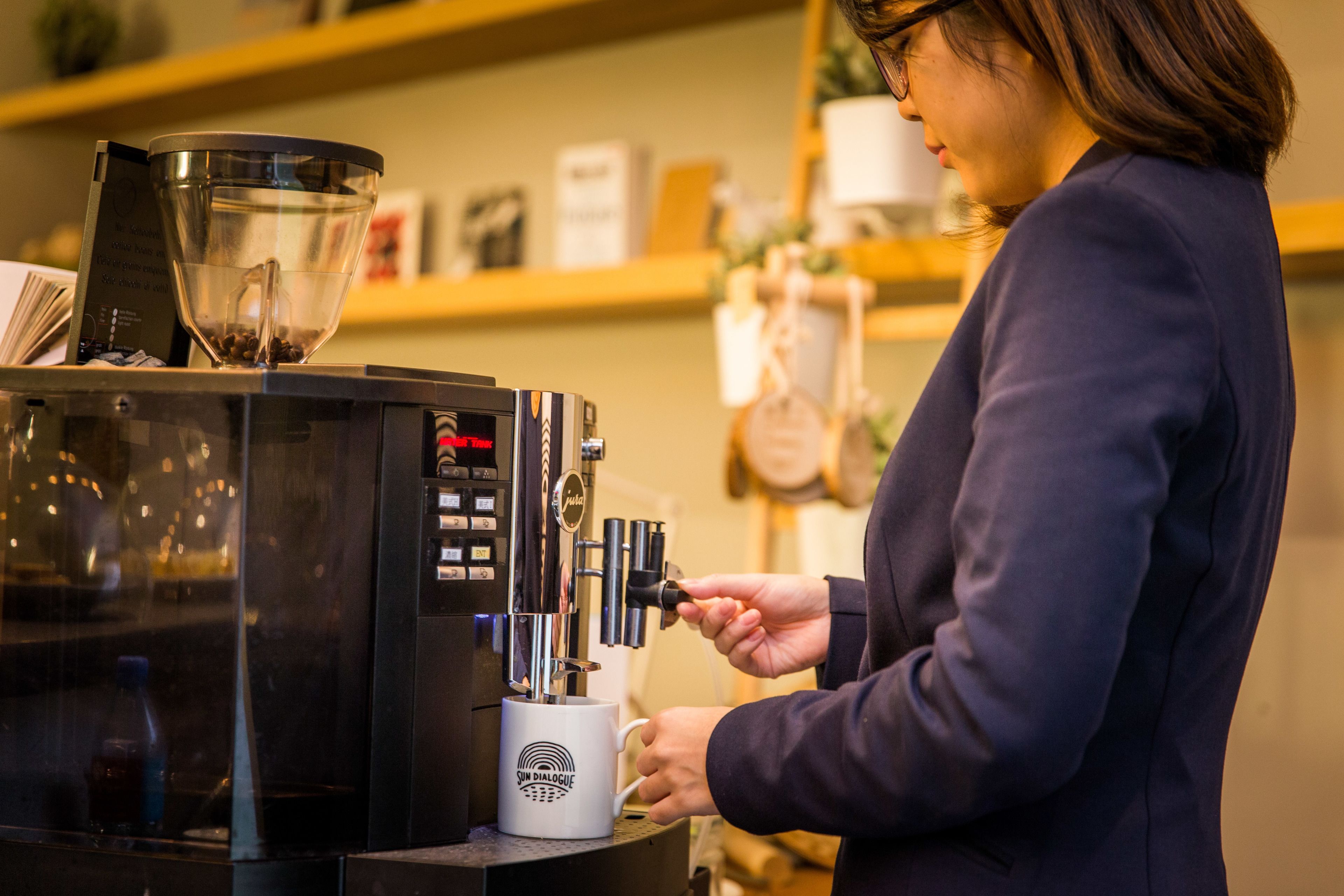 A person operating a coffee machine with a cup holder and a coffee grinder.