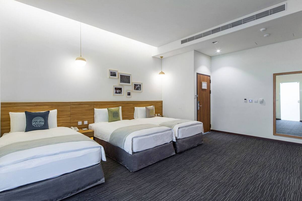 A hotel room with two beds, a wooden headboard, a large mirror, and a small desk with a mirror.