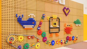 A pegboard with various colorful objects and structures, including gears, flowers, and a heart shape.