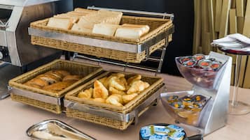 Een ontbijtbuffet met brood, gebak en diverse sauzen.