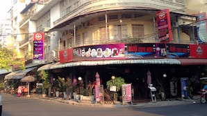 A multi-story building with a curved facade, balconies, and a prominent signboard advertising a restaurant.