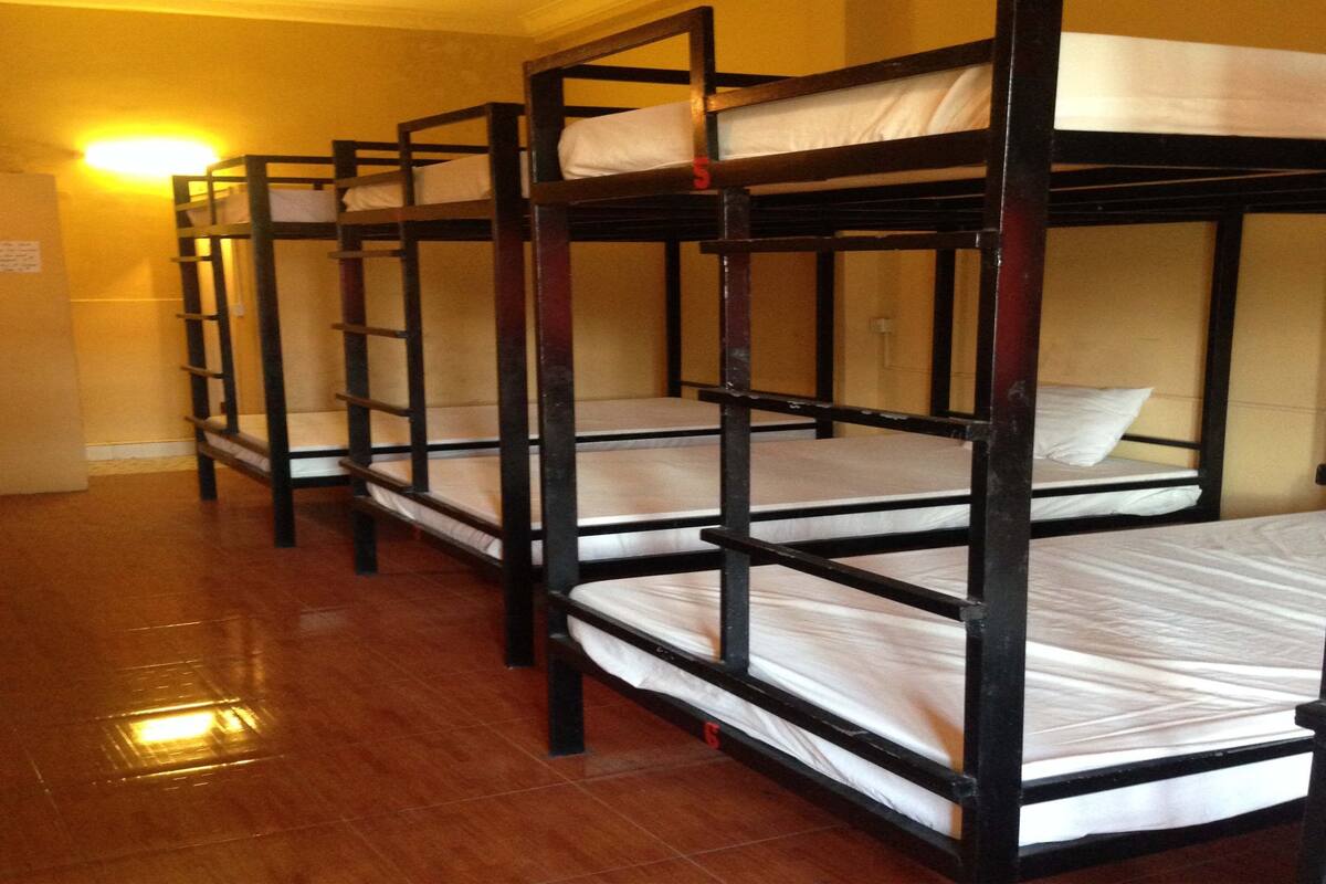 Bunk beds in a room with wooden floors and a wall-mounted light.