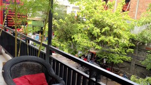 A balcony with a table and chairs, surrounded by greenery and buildings.