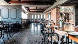 A spacious restaurant with high ceilings, exposed brick walls, and a mix of wooden and metal furniture. - Aquarius Hotel & Urban Resort Phnom Penh (Phnom Penh)