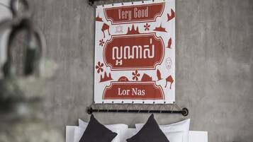 Una habitación de hotel con cama, almohadas y un adorno de pared con texto y símbolos.