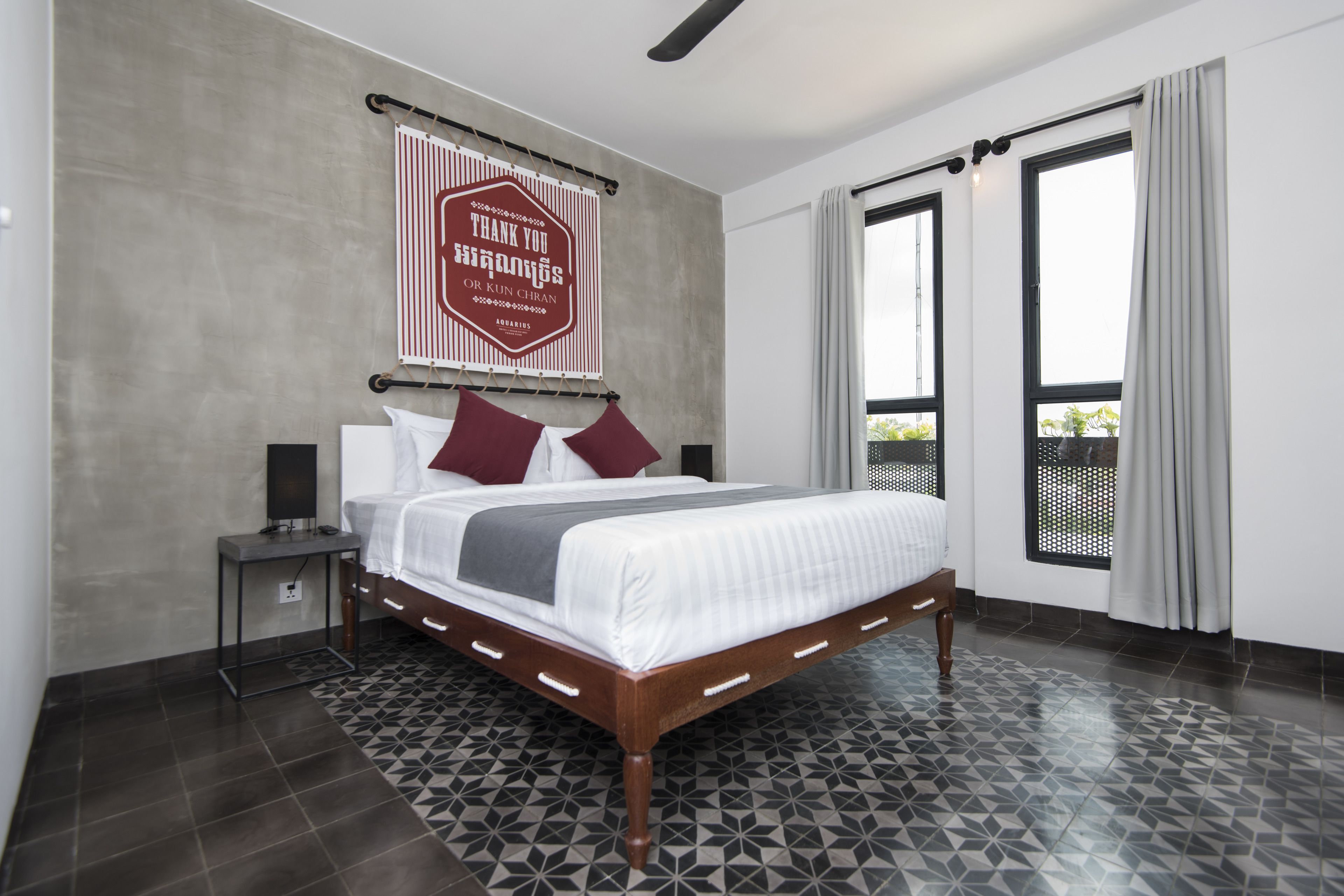 Una habitación de hotel moderna con una cama grande, una mesita de noche, un letrero en la pared y vistas por la ventana.
