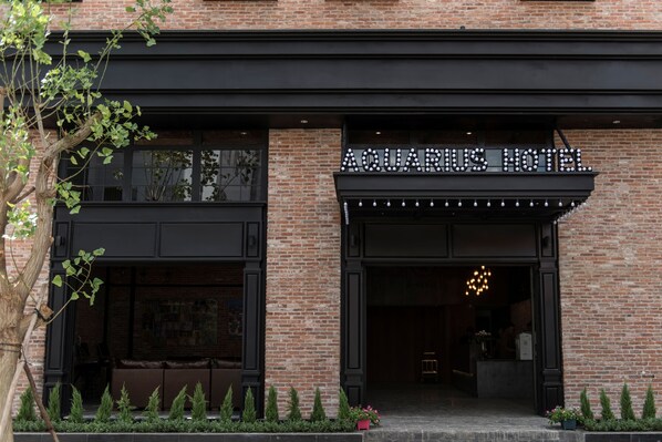 The exterior of the Aquarius Hotel with a brick facade, black trim, and a sign above the entrance. - Aquarius Hotel & Urban Resort Phnom Penh (Phnom Penh)