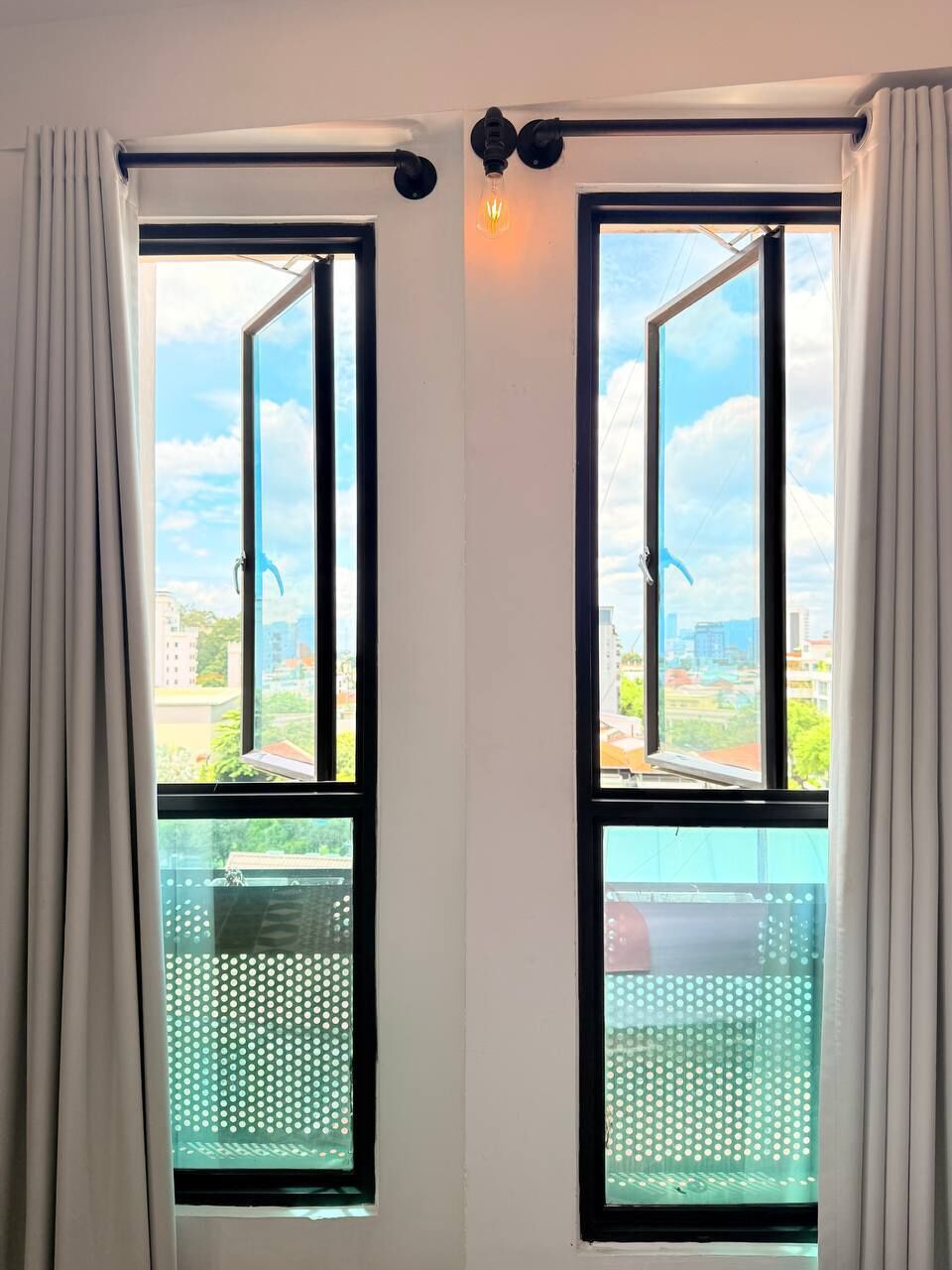 A room with two windows, a curtain rod, and a light fixture.