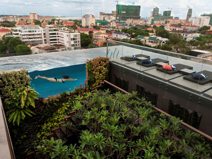 Una piscina al aire libre, sombrillas, sillones reclinables de piscina