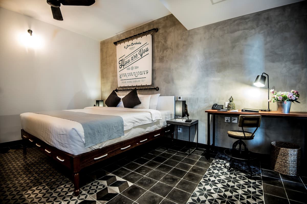 A modern bedroom with a bed, bedside table, lamp, and a decorative wall hanging.