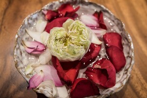 Een keramische schaal met een bloem en rozenblaadjes.