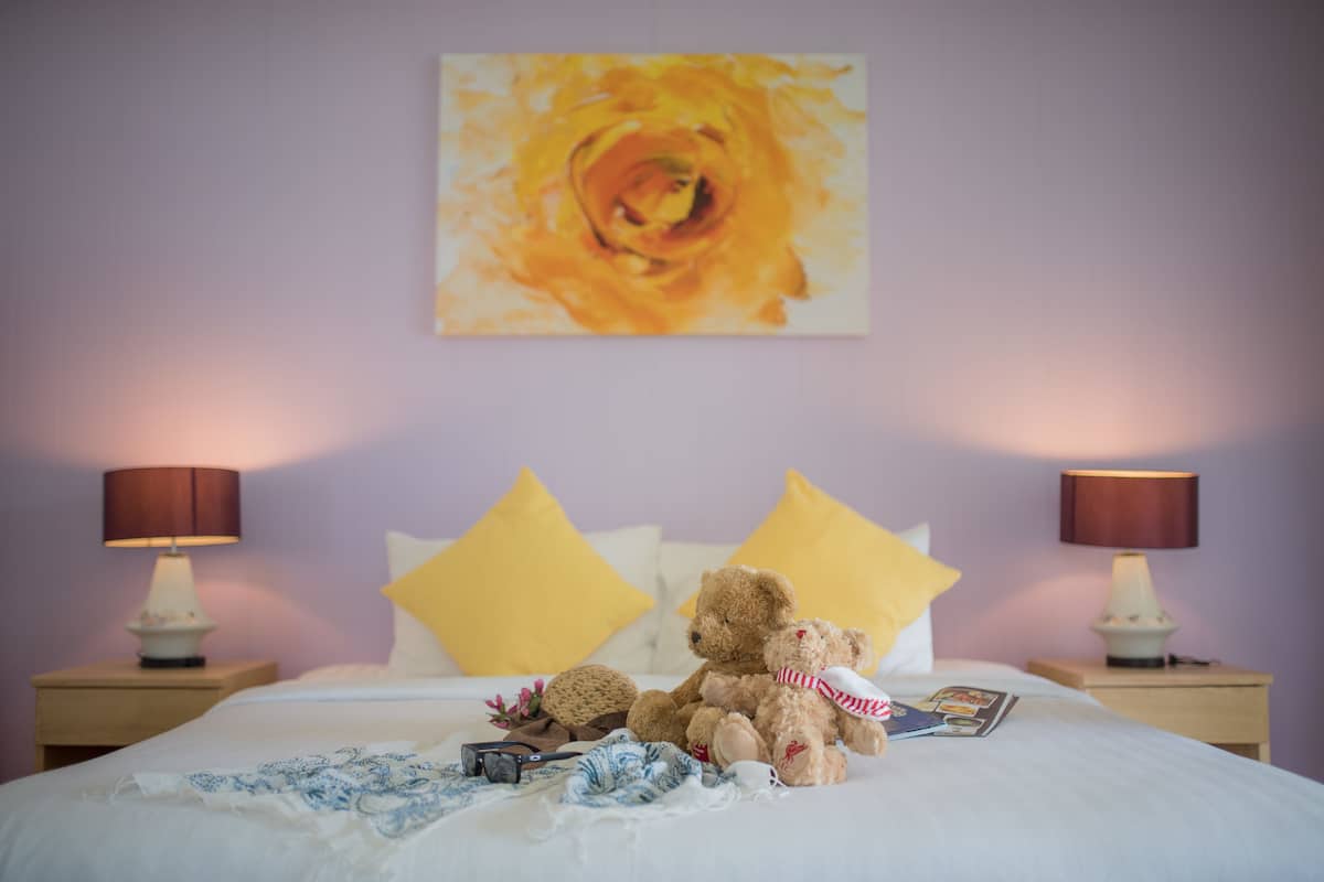Un lit avec deux ours en peluche, une lampe et un tableau accroché au mur.