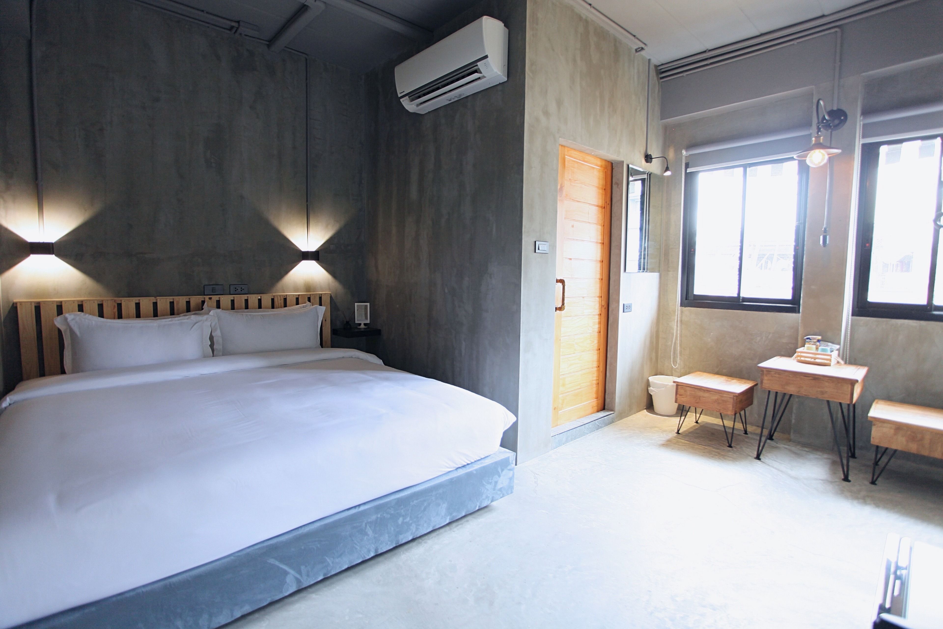 A bedroom with a large bed, bedside tables, a desk, and a window.