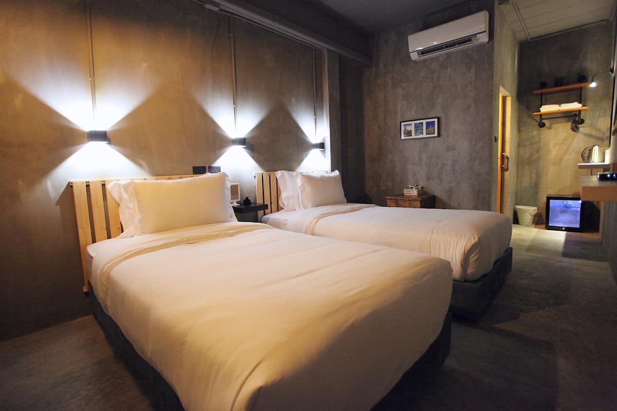 A hotel room with two beds, a desk with a computer, and a TV.
