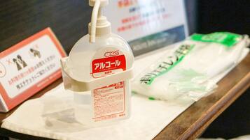 A bottle of Alcolol and a package of green tissue on a wooden surface.