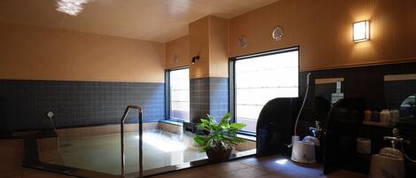 Un baño moderno con un jacuzzi de vidrio, un lavabo y una encimera con artículos de aseo.