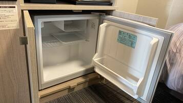 A compact refrigerator with a built-in ice maker, located in a small kitchen area with a wooden countertop and a towel rack above it.