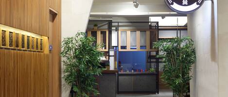 A modern interior with a wooden reception desk, potted plants, and a sign reading "FRESQA".