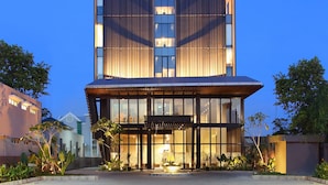 A modern hotel building with a prominent logo at the top.