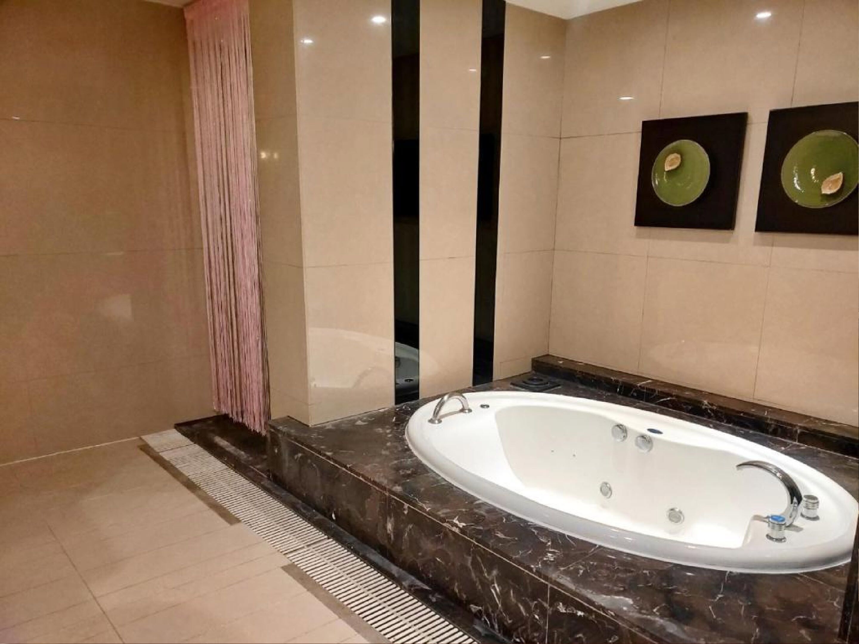 Een moderne badkamer met een groot ovaal bad, een douchegedeelte en twee wandgemonteerde wastafels.
