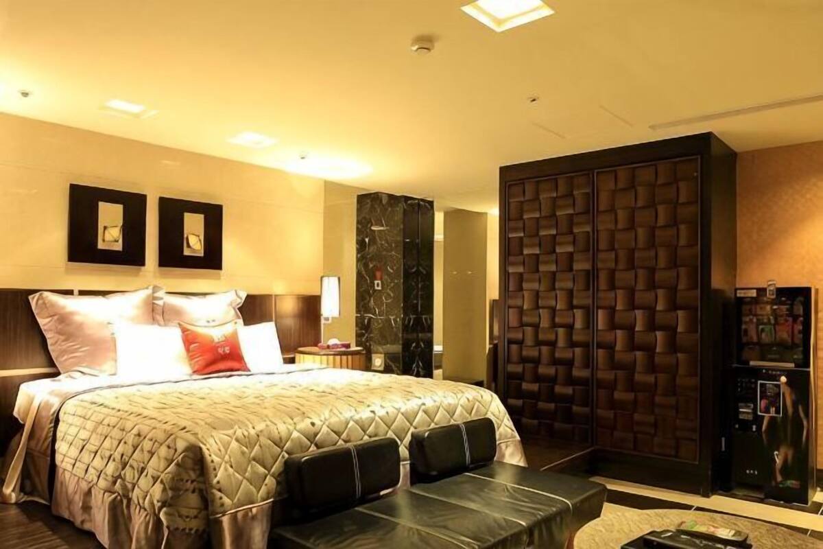 A hotel room with a bed, a desk, a wardrobe, and a TV.