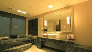 Un baño moderno con un espejo grande, una bañera y un tocador con lavamanos.
