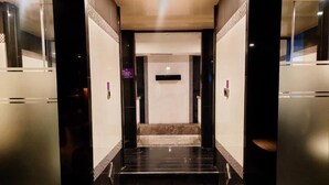 Un ascensor moderno con suelo de mármol y una zona central con alfombra estampada.